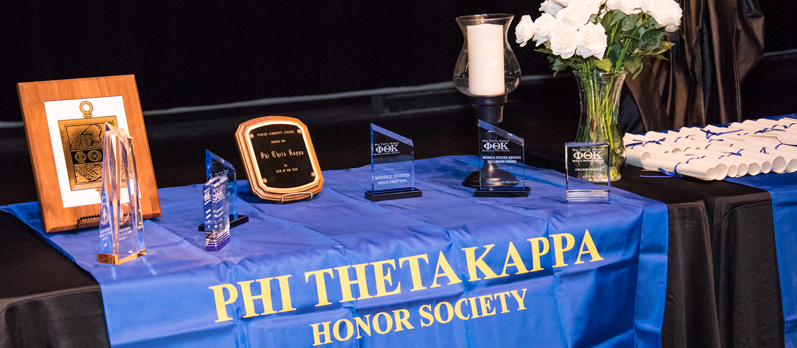 Awards and certificates displayed on a table at a Phi Theta Kappa honor society ceremony.