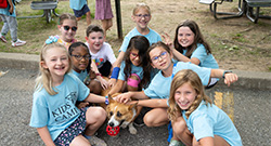 Several KOC students wearing blue shirts petting a dog.