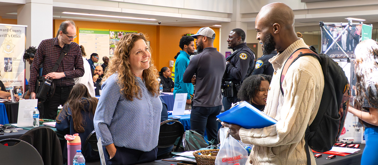 Job seekers talk with recruiters at information tables during a Howard Community College campus job fair.